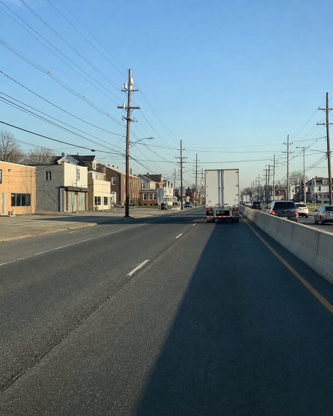 AI-generated divided urban-road scene with a truck, housing and utility poles, inspired by the Route 9 corridor. Not a verified Sayreville address, current map or real accident.